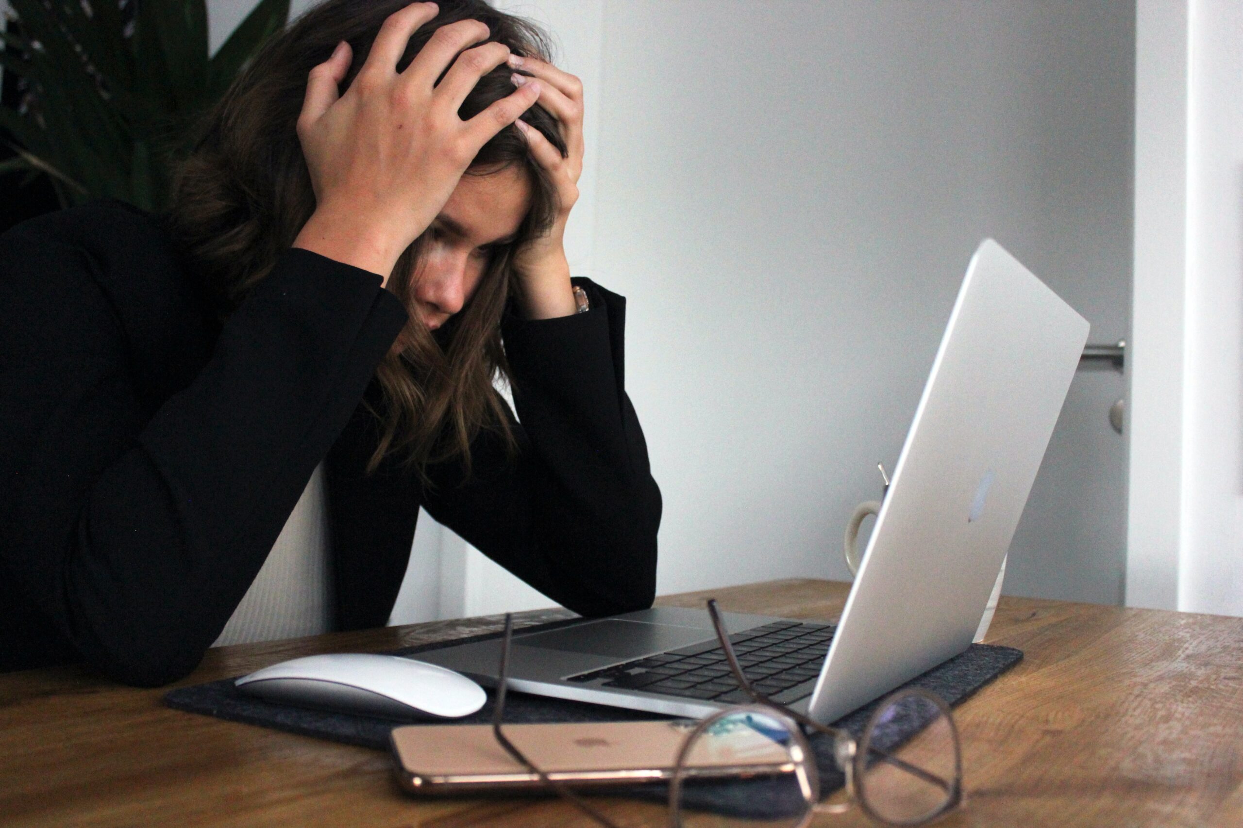 Girl holding her head looking stressed at her computer